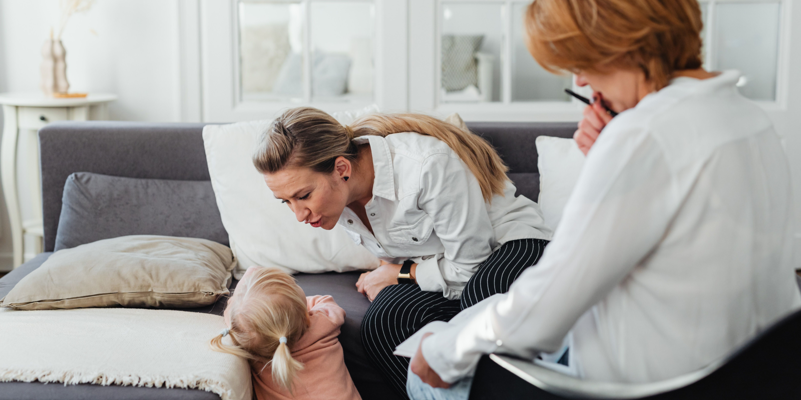 A parent meeting with a family support professional while interacting with her child during a home visit.